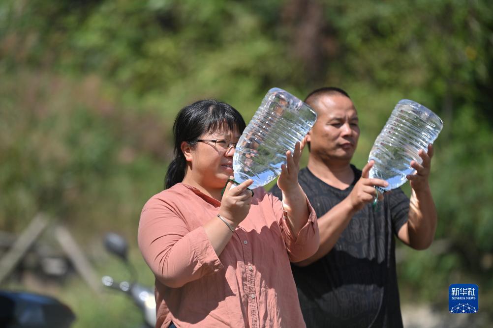 楊寧（左）在查看村民剛剛采集的水樣，為山泉水引水工程做準(zhǔn)備（10月8日攝）。新華社記者 黃孝邦 攝